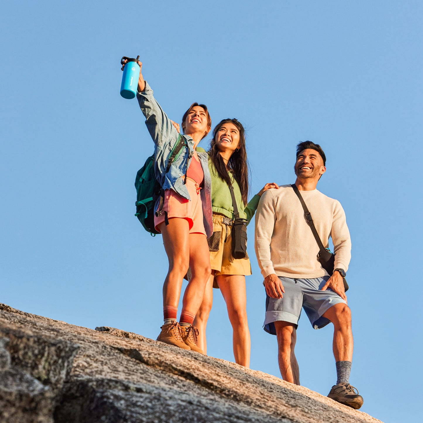 24oz Onyx Bottle Sling held by a female standing on a rock
