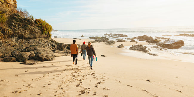 Three people walking on the beach with ThermoFlask bottles