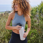 40oz Ice Grey/Azure Bottle with Spout Lids. Woman holding bottle while on a trail.