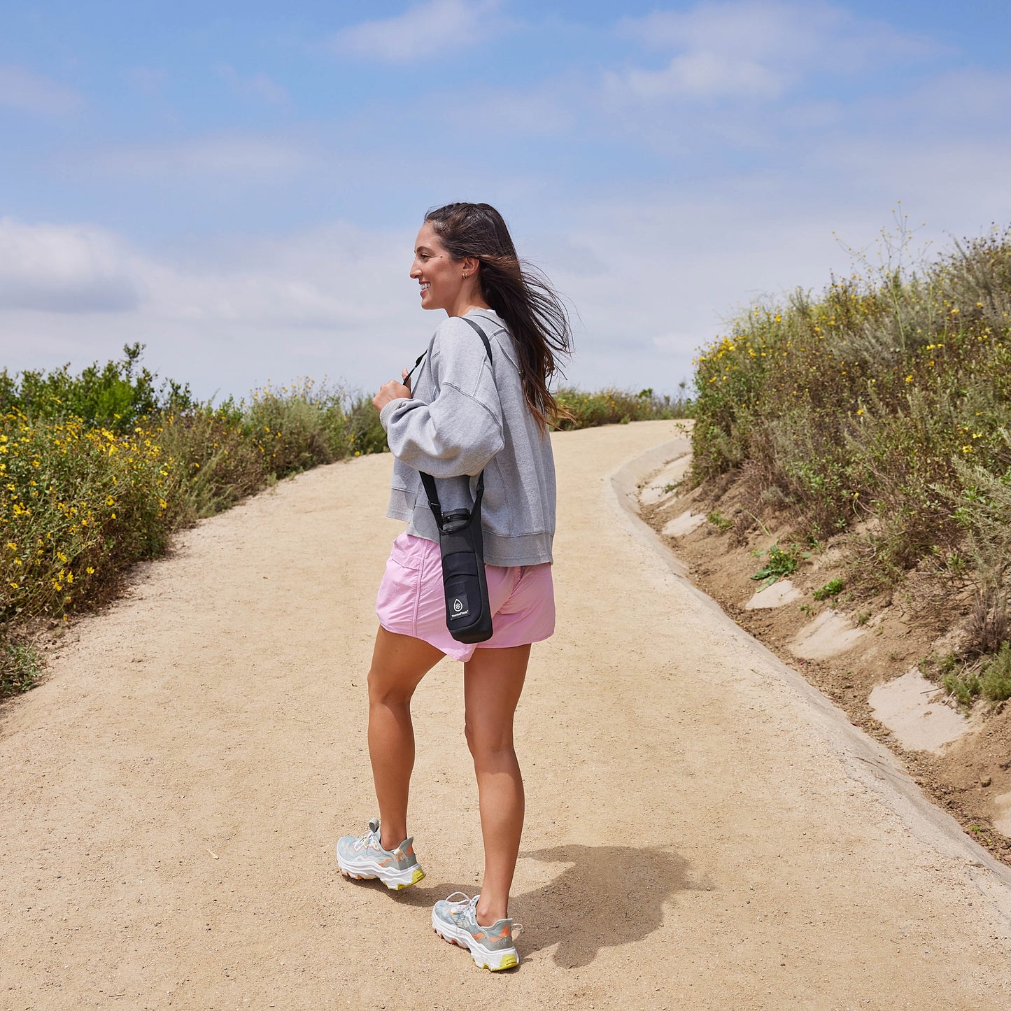 24oz Onyx Bottle Sling held by a female on a trail