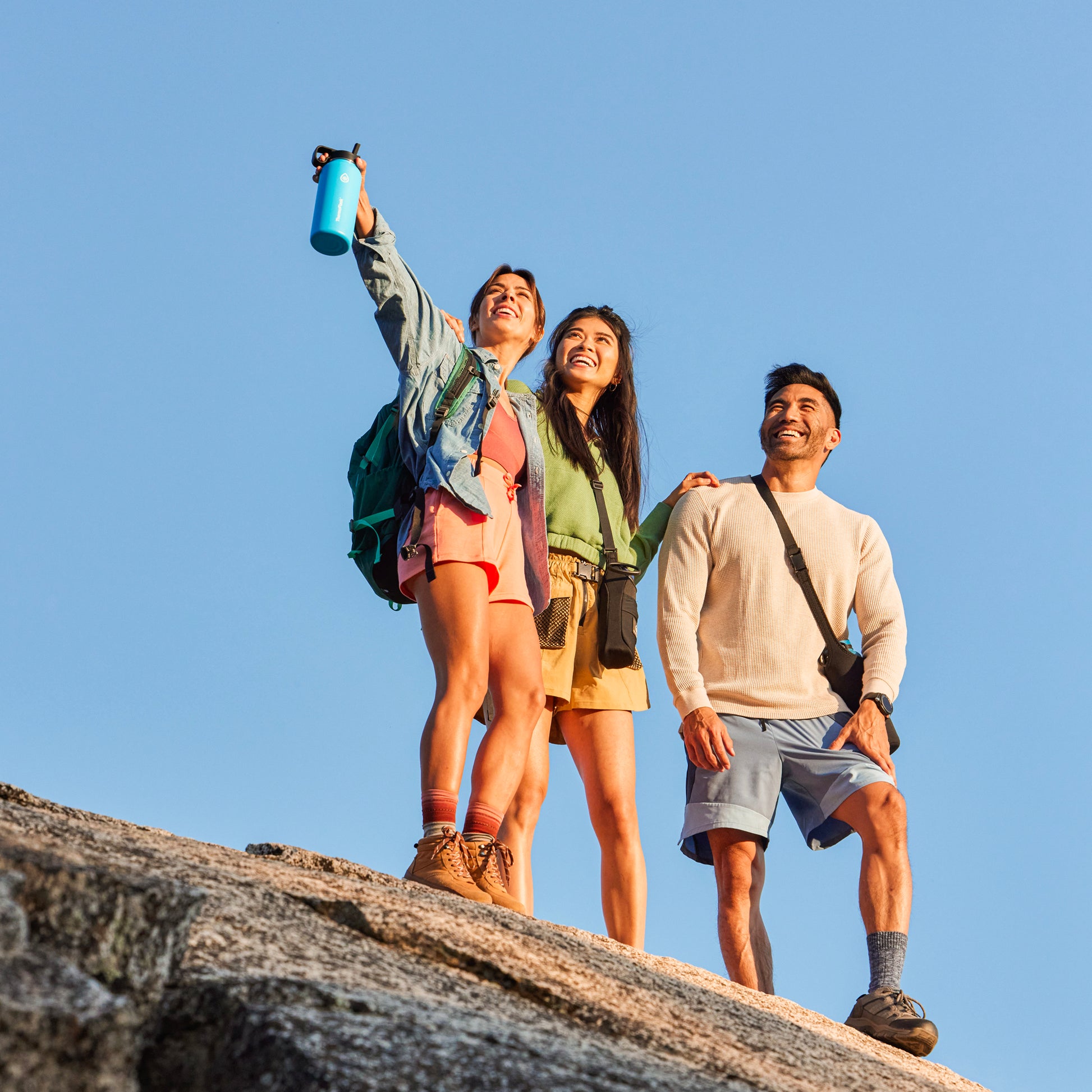 24oz Onyx Bottle Sling held by a female standing on a rock