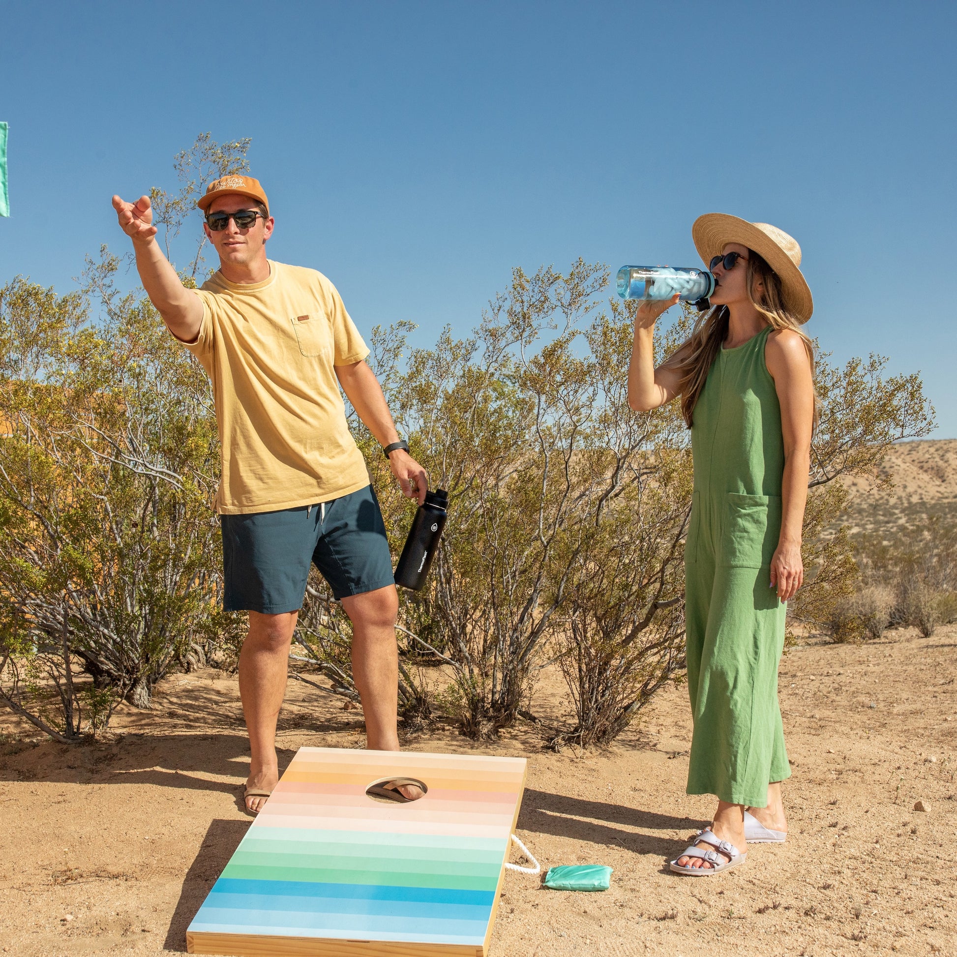 40oz Onyx chug bottle held by a man playing cornhole with a friend.